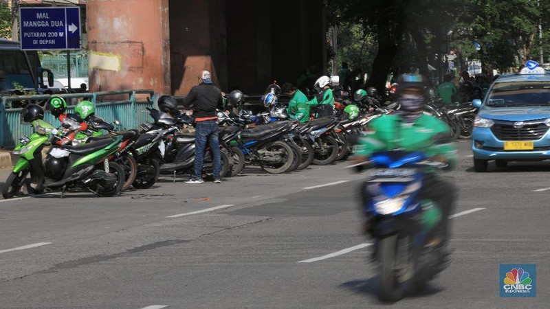 Pengemudi ojol memarkirkan motornya di tepi trotoar jalur Transjakarta di kawasan Mangga Dua.