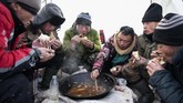 Para pekerja saat menikmati makan siang berupa ikan yang dipancing dari sungai. (NOEL CELIS / AFP)