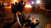 Pihak kepolisian mengatakan sembilan orang diamankan dan 12 orang terluka akibat bentrukan tersebut. (Photo by Pau Barrena / AFP)