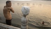 Seorang pria kedinginan di pinggir danau yang hampir membeku di musim dingin di Beijing, China. (AP/Ng Han Guan)
