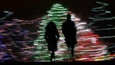 Bak lukisan, siluet warga terlihat di depan hiasan Natal di Lenexa, Kansas, AS. (AP Photo/Charlie Riedel)