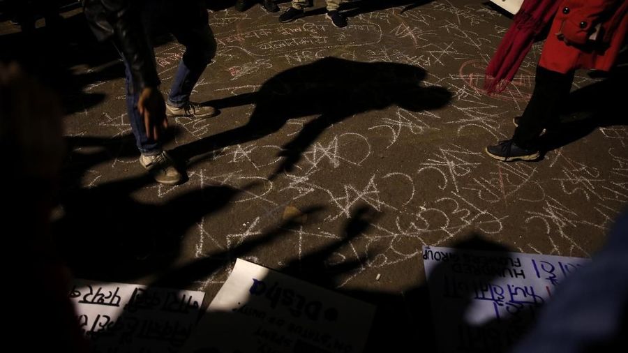 Shadows of protestors are cast on the ground with graffiti against the new citizenship law as they shout slogans near the Indian parliament in New Delhi, India, Thursday, Dec. 19, 2019. Police detained several hundred protestors in some of India's biggest cities Thursday as they defied a ban on assembly that authorities imposed to stem widespread demonstrations against a new citizenship law that opponents say threatens India's secular democracy. Dozens of demonstrations were to take place around country as opposition grows to a new citizenship law that excludes Muslims. The law has sparked anger at what many see as the government's push to bring India closer to a Hindu state. (AP Photo/Altaf Qadri)