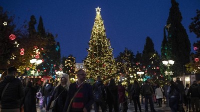 People walk in front of the Christmas tree at Syntagma square in central Athens, on Friday, Dec. 20, 2019. (AP Photo/Petros Giannakouris)
