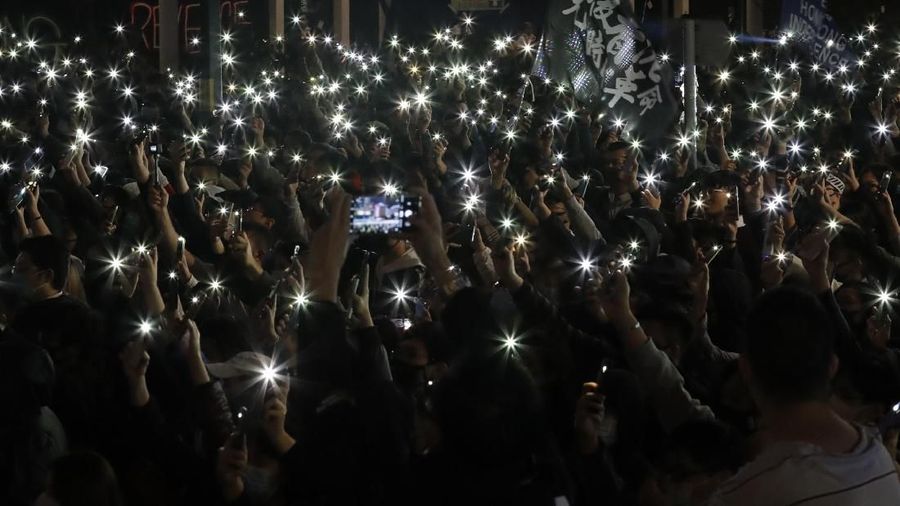 Peserta demonstrasi Hong Kong menyalakan senter dari smartphone.