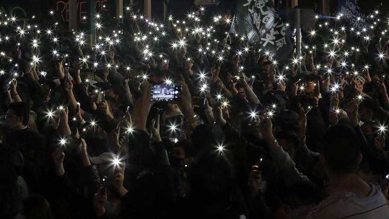 Peserta demonstrasi Hong Kong menyalakan senter dari smartphone.