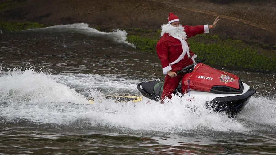 A firefighter dressed as Santa Claus drives a jet ski off Copacabana beach in Rio de Janeiro, Brazil, Wednesday, Dec. 18, 2019. Firefighters distributed Christmas gifts during an event for children with cancer. (AP Photo/Leo Correa)
