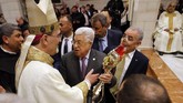 Presiden Palestina Mahmoud Abbas memegang sebuah peninggalan kayu yang terkenal sebagai bagian dari palungan Yesus pada Misa Natal di Betlehem, Rabu (25/12). (Mussa Qawasma/Pool Photo via AP)