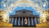 Seorang perempuan berjalan melewati dekorasi tahun baru di depan Teater Bolshoi di pusat kota Moskow, Rusia. (Photo by Yuri KADOBNOV / AFP)