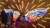 Pada malam natal di Beijing, China, seorang anak bereaksi melihat lampu neon yang berbentuk sayap. (AP Photo/Ng Han Guan)