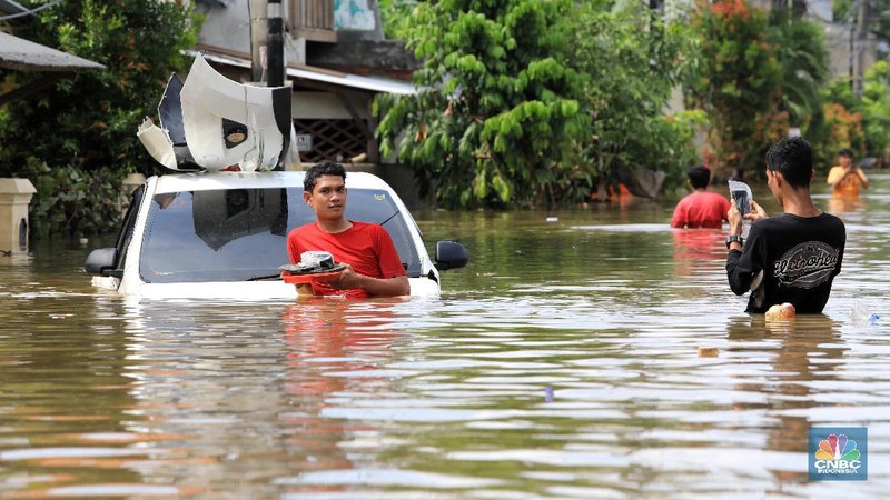 Warga memfoto mobil yang hanyut akibat banjir di Kawasan Ciledug Indah, Tangerang, Kamis (2/1/2020).