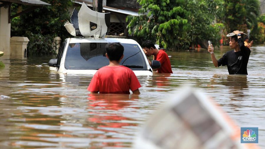 Warga memfoto mobil yang hanyut akibat banjir di Kawasan Ciledug Indah, Tangerang, Kamis (2/1/2020).