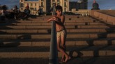 Seorang anak laki-laki berdiri di tangga di pantai Ramirez, saat matahari terbenam di Montevideo pada Sabtu (28/12). (Photo by Eitan ABRAMOVICH / AFP)