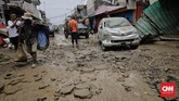 Lumpur menempel di kendaraan yang rusak dan bergelimpangan di sepanjang jalan. Sejumlah mobil dan bus ikut terbalik. (CNN Indonesia/Adhi Wicaksono)