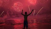Seorang pria menikmati kembang api di Pantai Copacabana selama perayaan Tahun Baru di Rio de Janeiro, Brasil pada Rabu (1/1) 2020. (AP Photo/Bruna Prado)