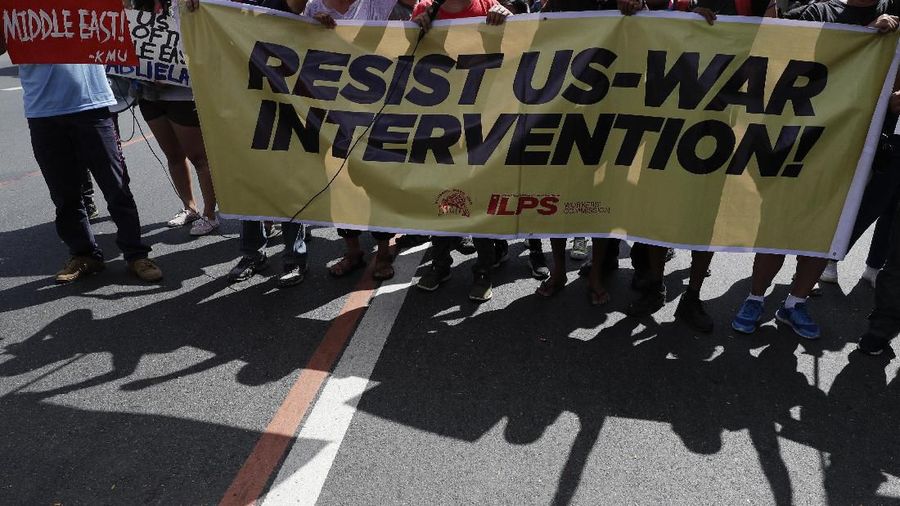 Pengunjuk rasa mengepalkan tangan mereka saat memegang spanduk yang menentang serangan AS  terhadap Iran di Manila, Filipina. (AP / Aaron Favila)