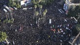 Sebagian besar warga mengenakan setelan hitam sambil membawa bendera Iran dan foto Soleimani, beberapa membawa poster bernada anti-Amerika. (Morteza Jaberian/Mehr News Agency via AP)