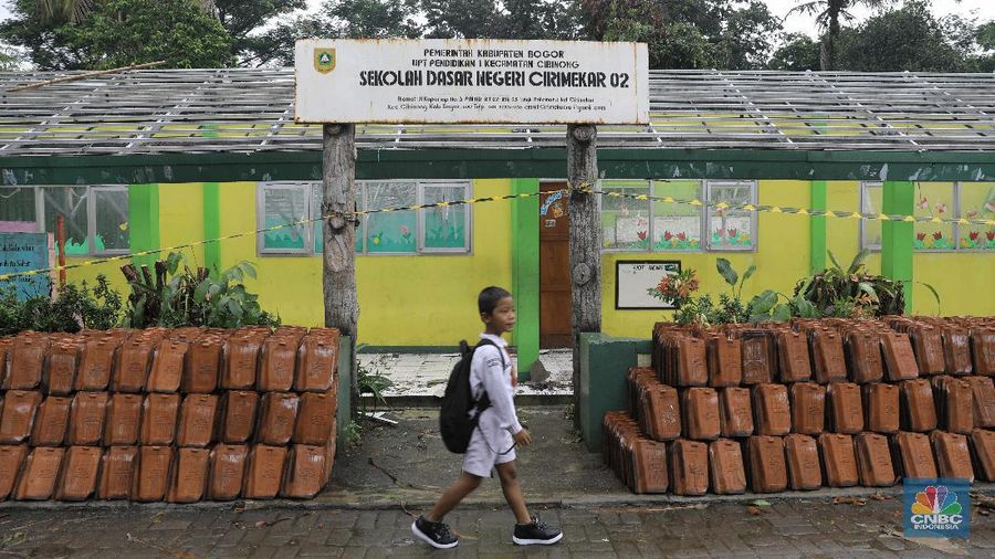 Pelajar melintas di Sekolah Dasar Negeri (SDN) Cirimekar 02 Cibinong, Kabupaten Bogor, Jawa Barat, Senin (6/1/2020). Sekolah tersebut  rusak berat akibat hujan yang mengguyur wilayah Jabodetabek pada 31 Desember 2019 hingga 1 Januari 2020. Pantauan վ ada lima ruang yang atapnya ambruk dihantam derasnya air hujan. Tiga ruang kelas, satu ruang guru, dan satu ruang komputer.(վ/Muhammad Sabki)
