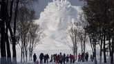 Turis berjalan di depan patung es menjelang pembukaan Festival Es dan Salju di Harbin, Heilongjiang, China, pada 4 Januari 2020. (NOEL CELIS / AFP)