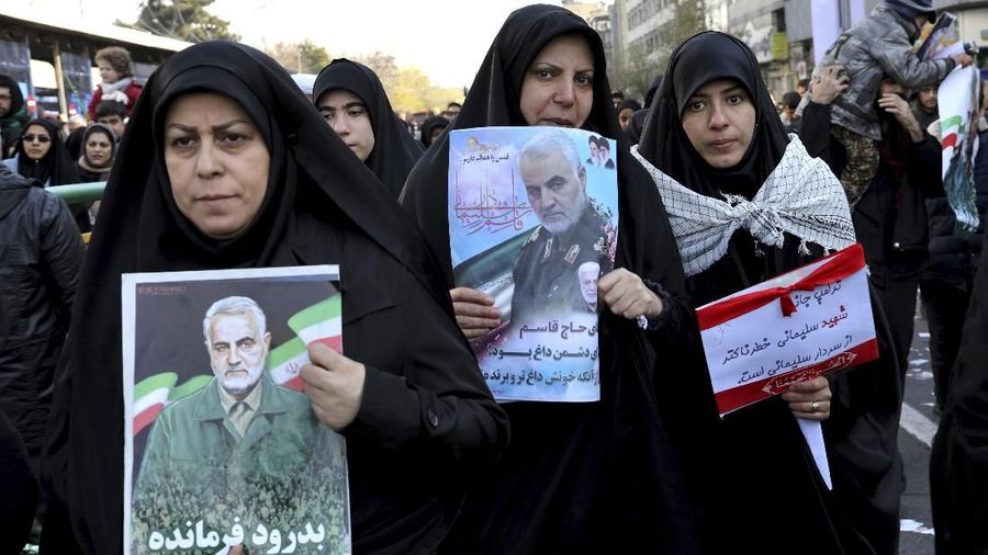 Pelayat yang memegang poster Jenderal Iran Qassem Soleimani saat menghadiri upacara pemakaman. (AP Photo/Ebrahim Noroozi)