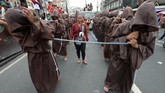 Para peserta yang memakai jubah warna coklat berjalan tanpa alas kaki, dalam harapan bisa menyentuh patung yang diberi nama Black Nazarene yang berusia ratusan tahun. (Photo by Ted ALJIBE / AFP)