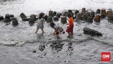Anak-anak bermain di pinggir laut saat gelombang air laut yang tinggi di kawasan Muara Baru, Jakarta, Kamis, 9 Januari 2020. (CNNIndonesia/Safir Makki)