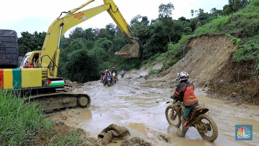 Warga membawa bantuan logistik di akses jalur utama menuju desa terisolasi di Kecamatan Sukajaya, Kamis (9/1/2020). Meski berlapis tanah dan lumpur jalur tersebut perlahan dapat mulai diakses kembali, setelah beberapa titik jalan putus akibat longsor sudah dibuka dengan alat berat. Kini akses jalan sudah sampai pada Desa Kiara Pandak, Kecamatan Sukajaya, Kabupaten Bogor. Jalur utama yang menghubungkan Desa Harkat Jaya-Kiara Pandak kini sudah dapat diakses dengan roda dua maupun roda empat. Hanya saja jalan utama tersebut masih berlapis tanah liat yang bervariatif ketebalannya. Selain akses yang sudah terbuka, bantuan logistik dan konsumsi melalui akses darat sudah masuk sampai Kampung Adat Urug sejak pagi tadi. Pantauan CNBC Indonesia sejumlah kendaraan bermotor dan mobil dibatu oleh TNI untuk menembus jalur tersebut. Satu per satu wilayah di Kecamatan Sukajaya, Kabupaten Bogor yang terisolasi akibat longsor, mulai bisa diakses. Dari yang sebelumnya enam desa: Kiarasari, Kiara Pandak, Urug, Cisarua, Cileuksa dan Pasir Madang, kini menyisakan tiga desa lagi. Yakni Desa Kiarasari, Cileuksa dan Cisarua. (CNBC Indonesia/Muhammad Sabki)