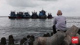 Warga menatap ke laut lepas, sementara kapal melempar sauh saat terjadi gelombang air laut tinggi di kawasan Muara Baru, Jakarta, Kamis, 9 Januari 2020. (CNNIndonesia/Safir Makki)