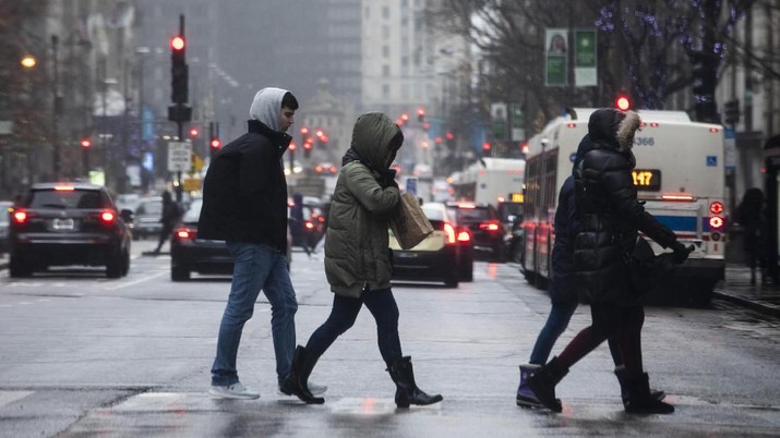 Pedestrians on the Magnificent Mile use their hoods to shield their faces as a winter storm moves through the Chicago area, Saturday, Jan. 11, 2020.   Freezing rain left roads and trees glazed with ice Saturday across parts of northern Illinois as a winter storm packing a mixed bag of precipitation cut power to about 5,000 homes and businesses across the region.  (Ashlee Rezin Garcia /Chicago Sun-Times via AP)