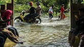 Karena banjir, jalan sempat terputus. Warga menembus jalan desa yang terendam banjir akibat jebolnya tanggul Sungai Tuntang di Desa Tlogorejo, Guntur, Kabupaten Demak, Jawa Tengah, Minggu (12/1/2020). ANTARA FOTO/Aji Styawan