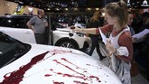 Pendemo menuangkan cara warna merah sebagai bentuk protes mereka kepada perusahaan otomotif. (Photo by FranÁois WALSCHAERTS / AFP)