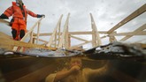 Seorang pekerja bersiaga sementara penganut Kristen Orthodox di Rusia mencelupkan diri pada sungai Neva yang membeku di St. Petersburg, Rusia. (AP Photo/Dmitri Lovetsky)