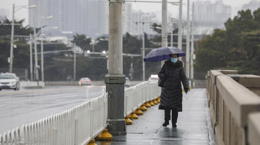 A woman wearing a face mask walks across a bridge in Wuhan in central China's Hubei province, Saturday, Jan. 25, 2020. The virus-hit Chinese city of Wuhan, already on lockdown, banned most vehicle use downtown and Hong Kong said it would close schools for two weeks as authorities scrambled Saturday to stop the spread of an illness that is known to have infected more than 1,200 people and killed 41, according to officials. . (Chinatopix via AP)