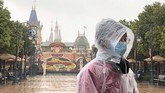 Pekerja Shanghai Disney Resort berdiri di depan pintu masuk taman bermain yang ditutup sejak Sabtu (25/1) demi menghindari mewabahnya virus corona. (AP Photo/Fu Ting)