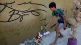Seorang bocah menaruh bunga di depan sebuah gambar Kobe Bryant yang dipenuhi tanda tangan di 'House of Kobe' di Valenzuela, Manila, Filipina. Bryant meninggal dunia karena kecelakaan helikopter bersama tujuh penumpang lain. (AP Photo/Aaron Favila)