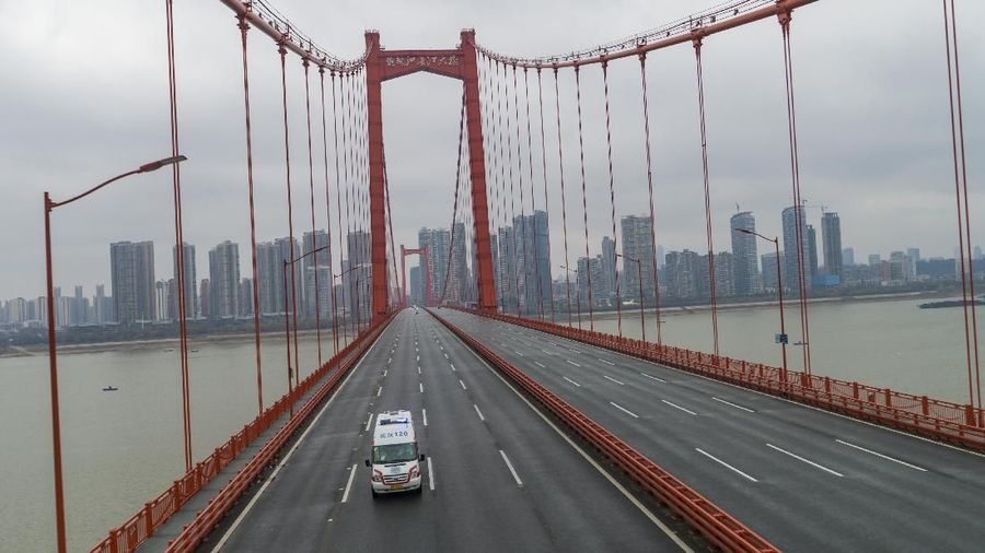 In this Saturday, Jan. 25, 2020 photo, an ambulance drives across a nearly empty bridge in Wuhan in central China's Hubei Province. A new viral illness being watched with a wary eye around the globe accelerated its spread in China on Sunday with 56 deaths so far, while the U.S. Consulate in the city at the epicenter announced it will evacuate its personnel and some private citizens aboard a charter flight. (Chinatopix via AP)
