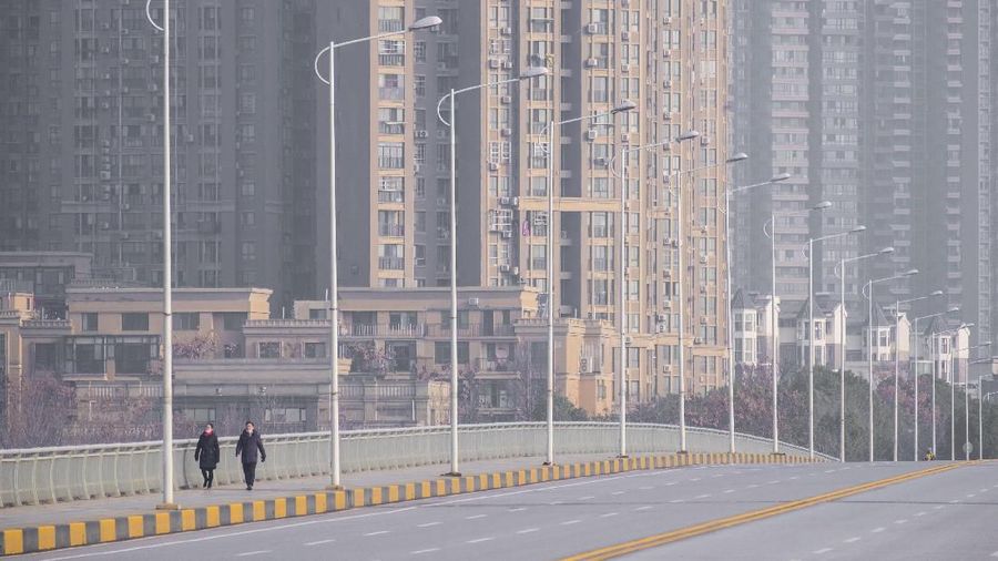 People wearing face masks walk down a deserted street in Wuhan in central China's Hubei Province, Tuesday, Jan. 28, 2020. China's death toll from a new viral disease that is causing a  global concern rose by 25 to at least 106 on Tuesday as the United States and other governments prepared to fly their citizens out of the locked-down city at center of the outbreak. (AP Photo/Arek Rataj)