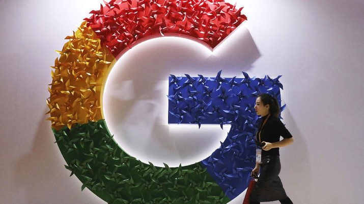 FILE - In this Monday, Nov. 5, 2018, file photo, a woman walks past the logo for Google at the China International Import Expo in Shanghai. Chinese tech giant Huawei is racing to develop replacements for Google apps. U.S. sanctions imposed on security grounds block Huawei from using YouTube and other popular Google 