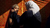 Seorang perempuan membantu model untuk persiapan sebuah pertunjukan busana di Kabul, Afghanistan pada Kamis (23/1). (AP Photo/Tamana Sarwary)