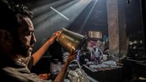 Mohamed Kamel (36) menuangkan air dari ember ke tong untuk mewarnai benang di bengkel tradisional yang sekarat di ibukota Mesir Distrik Darb al-Ahmar pada Selasa (21/1). (Khaled DESOUKI / AFP)