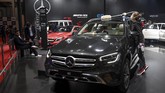 Seorang wanita menggunakan masker membersihkan mobil display merek Mercedes-Benz. (Photo by Money SHARMA / AFP)