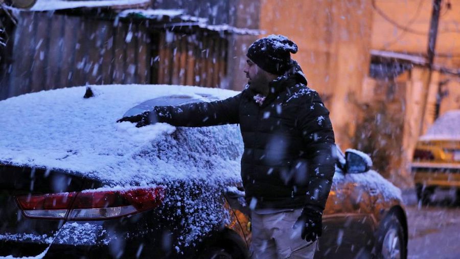 A man walks on a road while it snows in Baghdad, Iraq, Tuesday, Feb. 11, 2020. (AP Photo/Hadi Mizban)