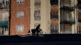 Refleksi dari seorang pengendara sepeda saat ia mengayuh pedalnya di kanal Naviglio di Milan, Italia, Selasa, (11/2) (AP Photo/Luca Bruno).