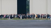 Sejumlah WNI yang dievakuasi dari Wuhan, China melambaikan tangan ke arah media saat akan senam bersama prajurit TNI pada hari ke-13 masa observasi di Hanggar Pangkalan Udara TNI AU Raden Sadjad, Ranai, Natuna, Jumat (14/2). (ANTARA FOTO/Muhammad Adimaja/foc).
