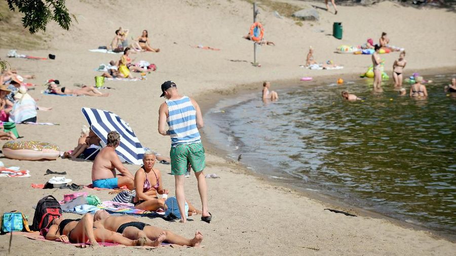 Sunbathers enjoy the hot weather as they sit on a beach in Vaasa, Finland, Thursday, July 19, 2018. (Mikko Stig/Lehtikuva via AP)