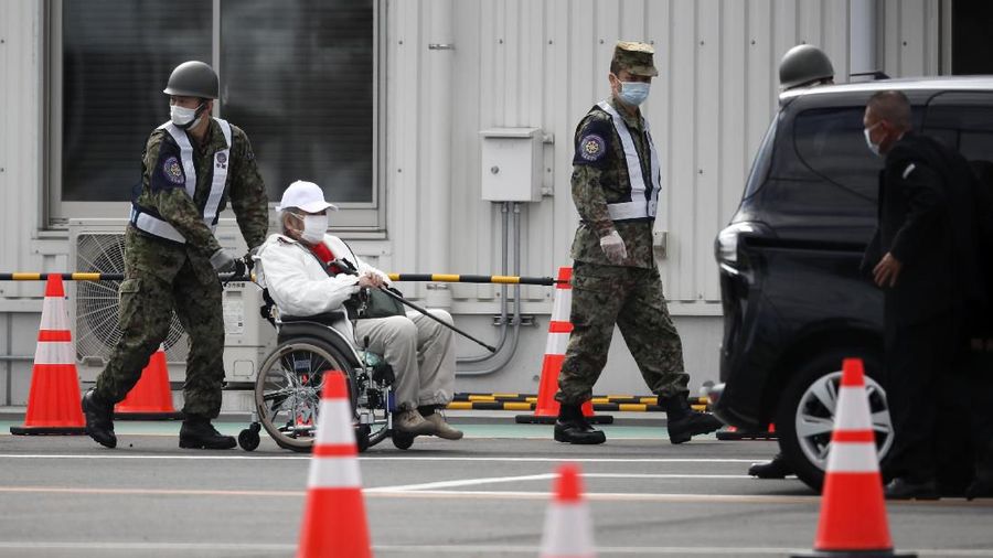 An unidentified passenger is surrounded by the media after she disembarked from the quarantined Diamond Princess cruise ship Wednesday, Feb. 19, 2020, in Yokohama, near Tokyo. Passengers tested negative for COVID-19 started disembarking Wednesday. (AP Photo/Jae C. Hong)
