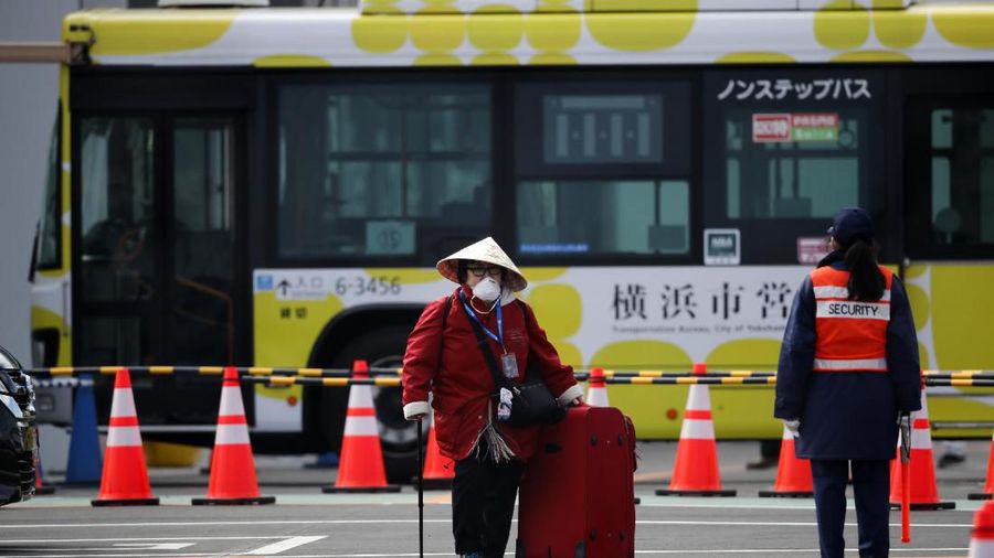 An unidentified passenger is surrounded by the media after she disembarked from the quarantined Diamond Princess cruise ship Wednesday, Feb. 19, 2020, in Yokohama, near Tokyo. Passengers tested negative for COVID-19 started disembarking Wednesday. (AP Photo/Jae C. Hong)