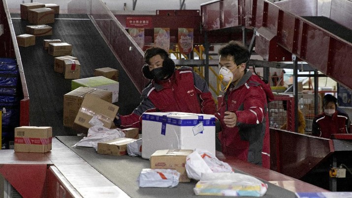 Penjualan Online di China Saat Maraknya Virus Corona. (AP Photo/Ng Han Guan)( In this Tuesday, Feb. 18, 2020, photo, a resident looks for her parcel near a temporary No Contact parcel collection point for Chinese e-commerce giant JD.com outside an apartment complex in Beijing, China. JD and rivals including Pinduoduo, Miss Fresh and Alibaba Group's Hema are scrambling to fill a boom in orders while protecting their employees. E-commerce is one of the few industries to thrive after anti-virus controls starting in late January closed factories, restaurants, cinemas, offices and shops nationwide and extinguished auto and real estate sales. (AP Photo/Ng Han Guan)