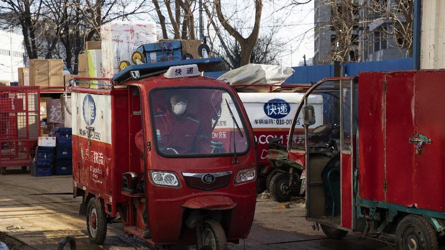 In this Tuesday, Feb. 18, 2020, photo, a resident looks for her parcel near a temporary No Contact parcel collection point for Chinese e-commerce giant JD.com outside an apartment complex in Beijing, China. JD and rivals including Pinduoduo, Miss Fresh and Alibaba Group's Hema are scrambling to fill a boom in orders while protecting their employees. E-commerce is one of the few industries to thrive after anti-virus controls starting in late January closed factories, restaurants, cinemas, offices and shops nationwide and extinguished auto and real estate sales. (AP Photo/Ng Han Guan)