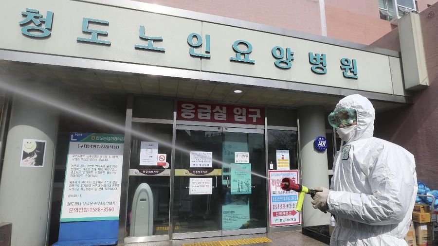 A worker wearing protective gears sprays disinfectant against the new coronavirus in front of the Daenam Hospital in Cheongdo, South Korea, Friday, Feb. 21, 2020. South Korea on Friday declared a 
