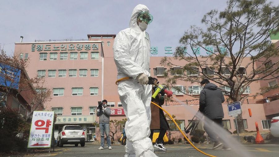 A worker wearing protective gears sprays disinfectant against the coronavirus in front of the Daenam Hospital in Cheongdo, South Korea, Friday, Feb. 21, 2020. South Korea on Friday declared a